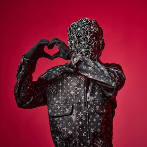 rapper in mask wearing Louis Vuitton on red background