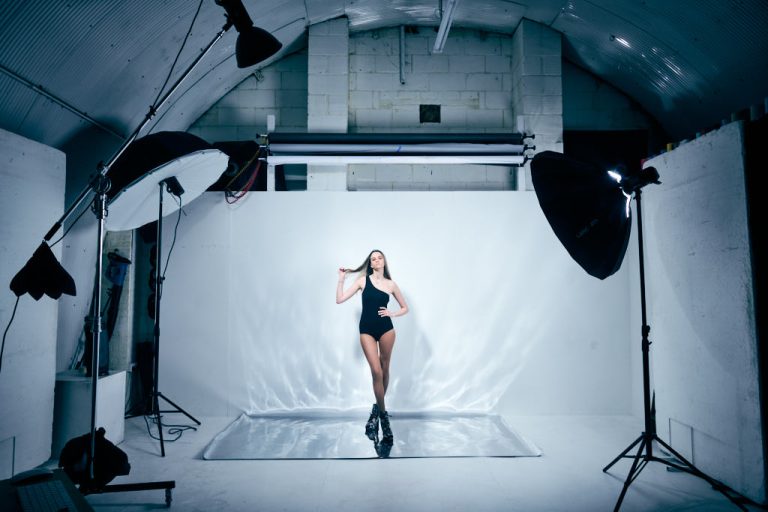 studio lights BTS with model standing on mirror fabric